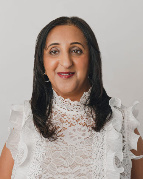 headshot for Anu Pala, a South Asian woman with shoulder-length brown hair, wearing a white blouse