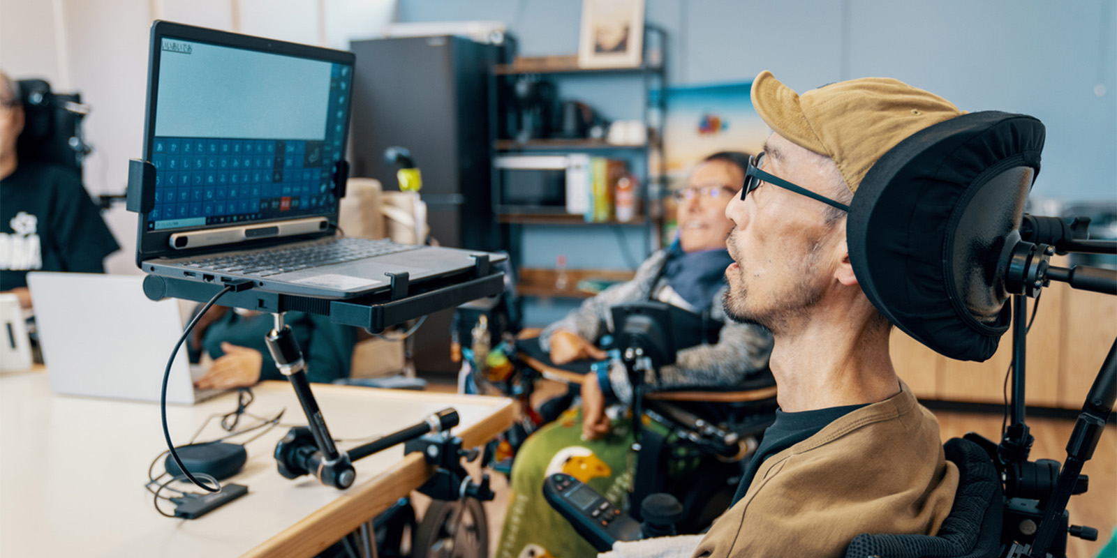 Office worker using a motorized wheelchair is using assistive technology to access the internet.