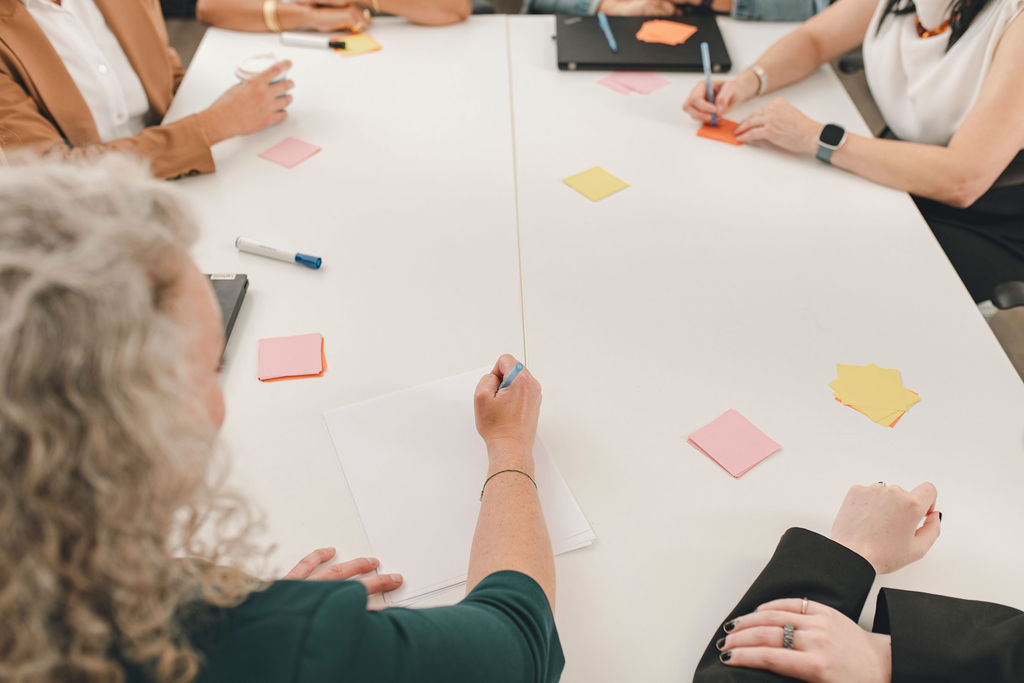 a group of designers brainstorming on post in notes around a white table